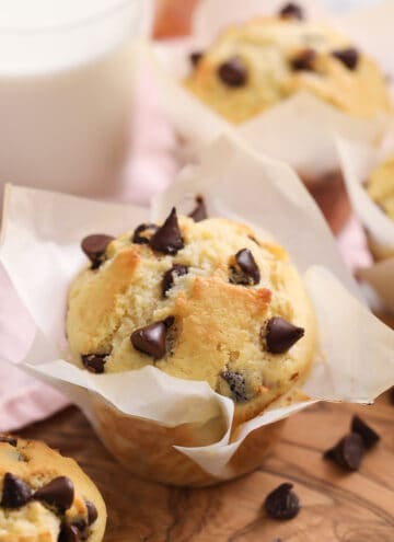 Chocolate Chip Muffins on a wooden board next to a glass of milk.