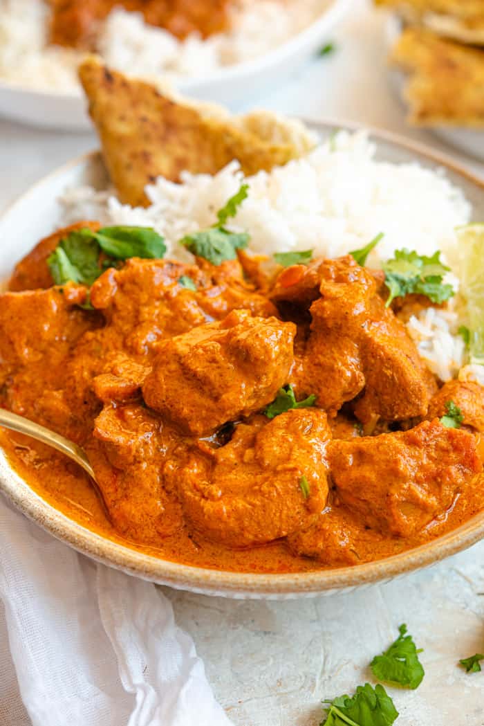 A close up of chicken tikka masala in a bowl with rice