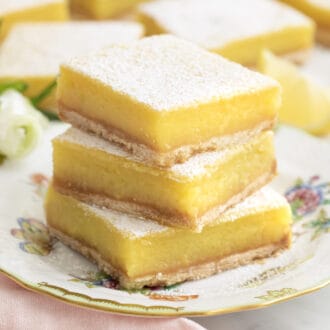 A stack of lemon bars on a porcelain plate.
