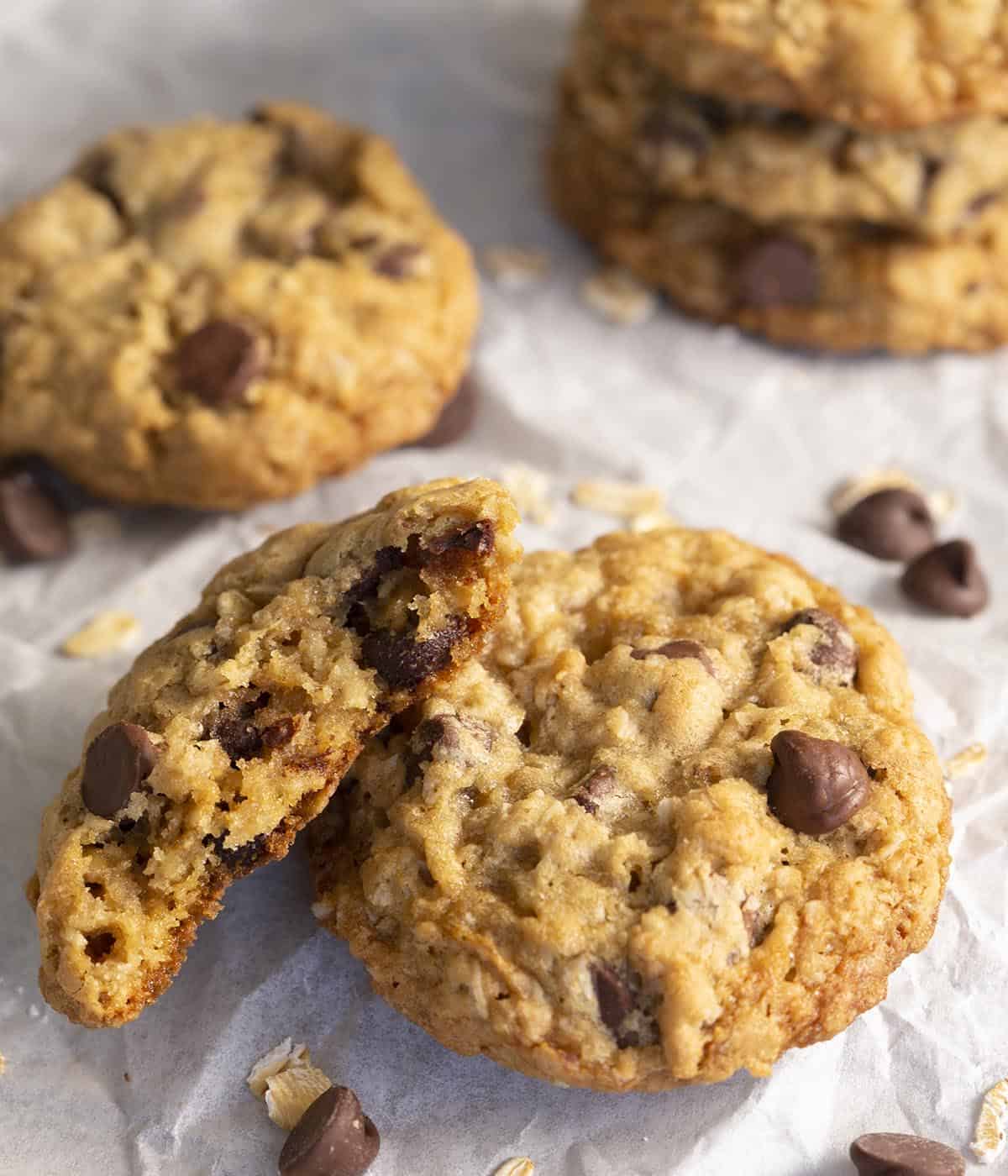 A group of Oatmeal Chocolate Chip cookies with on broken in half to show the chewy interior.