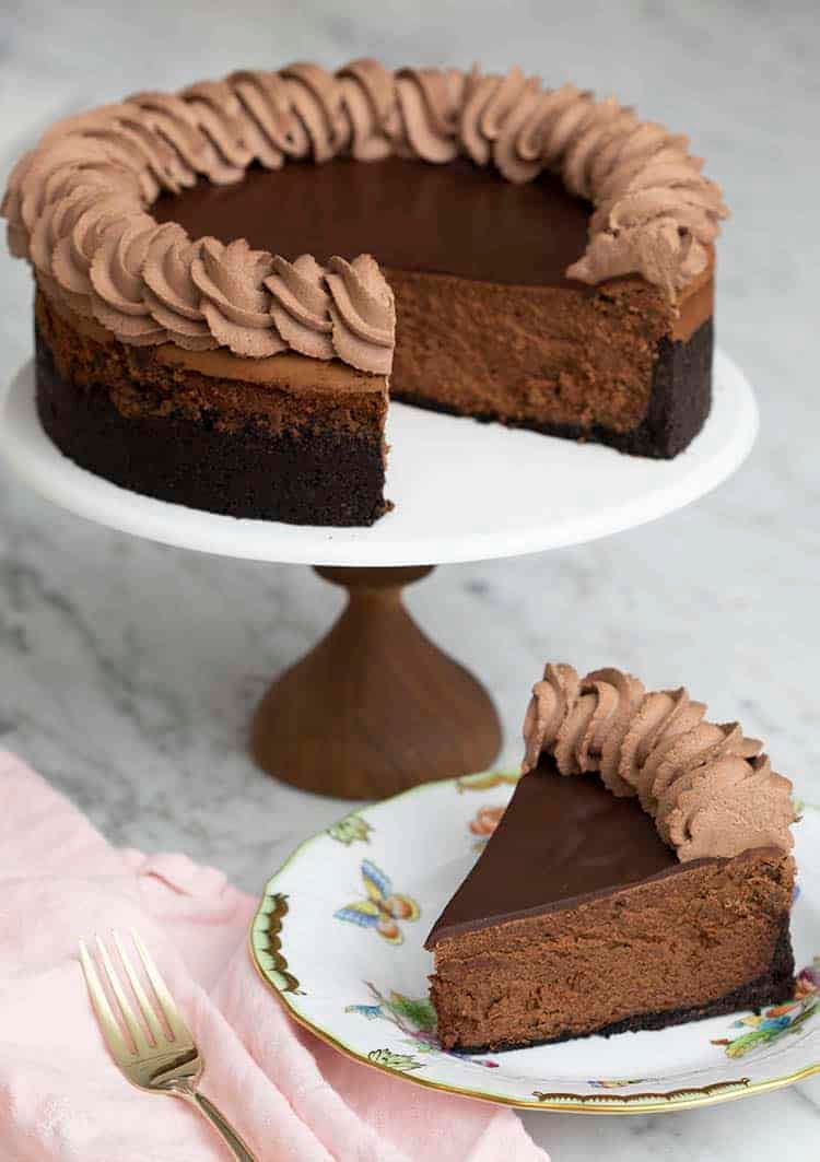 A chocolate cheesecake with chocolate ganache and chocolate whipped cream piped on top.