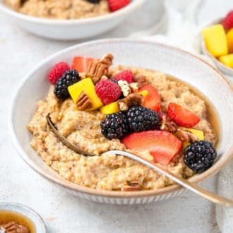 A bowl of Instant Pot steel cut oats with an assortment of toppings with a spoon inside.