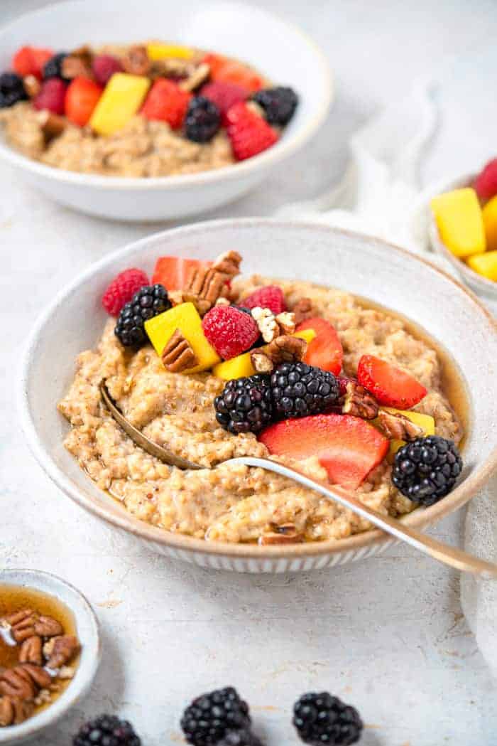 A side shot of cooked steel cut oats in a bowl topped with fruit