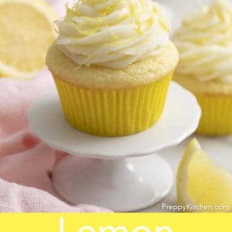 Pinterest graphic of a lemon cupcake with lemon frosting and zest. More cupcakes in the background and cut lemons.