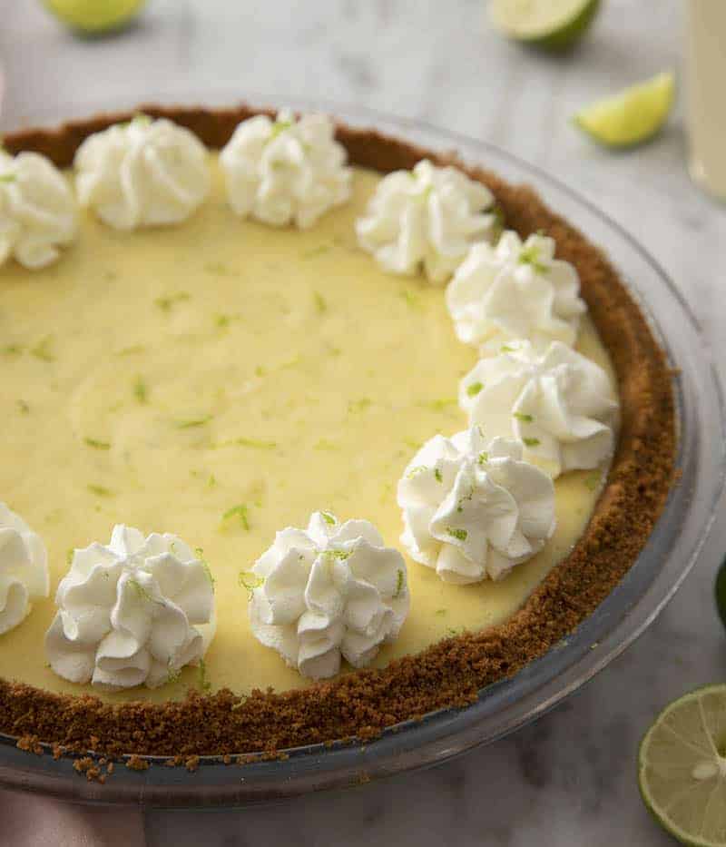 A closeup of a key lime pie with whipped cream dollops.