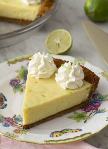 A slice of key lime pie topped with whipped cream and lime zest.