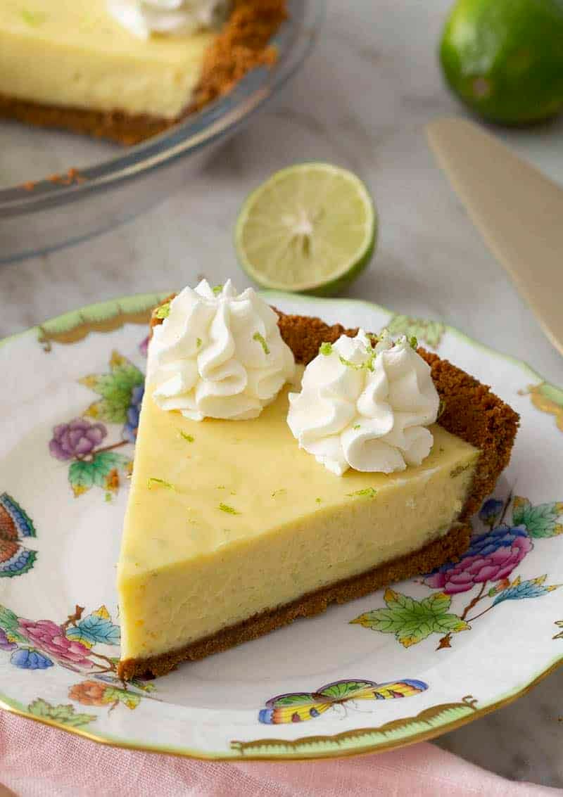 A slice of key lime pie topped with whipped cream and lime zest.