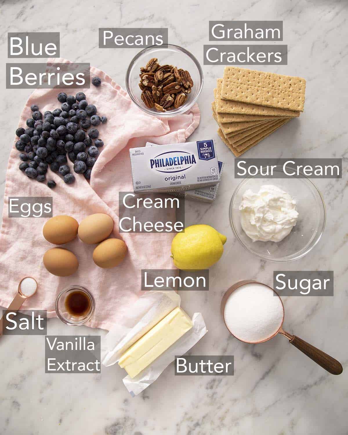 Ingredients for making blueberry mini cheesecakes on a counter.