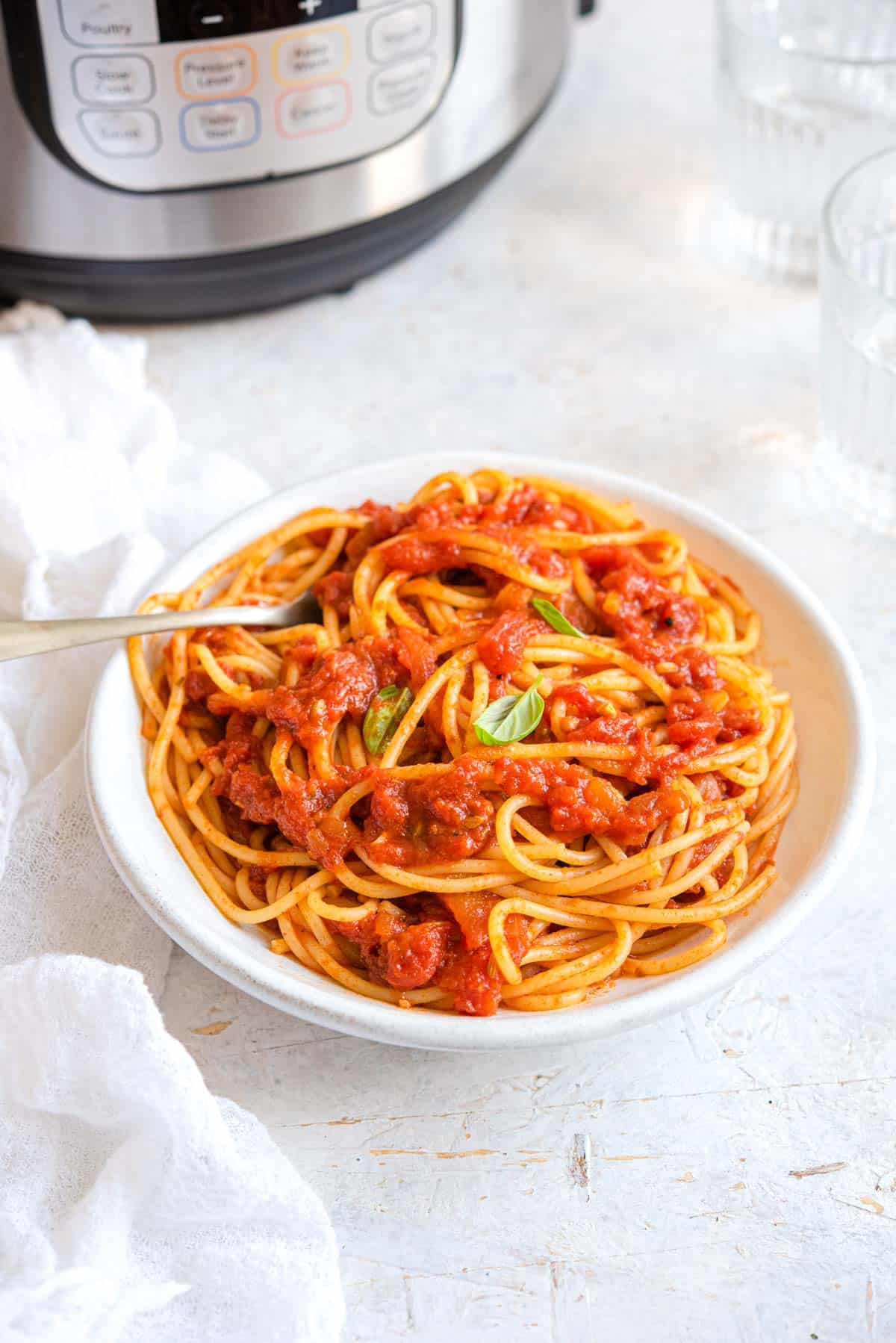 Spaghetti with tomato sauce in a bowl with an Instant Pot in the background