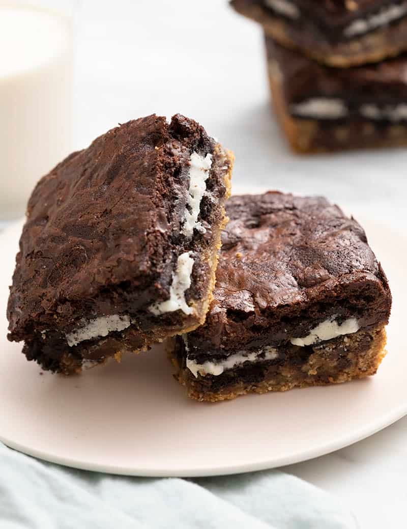 Slitty brownies on a light pink plate next to a glass of milk.
