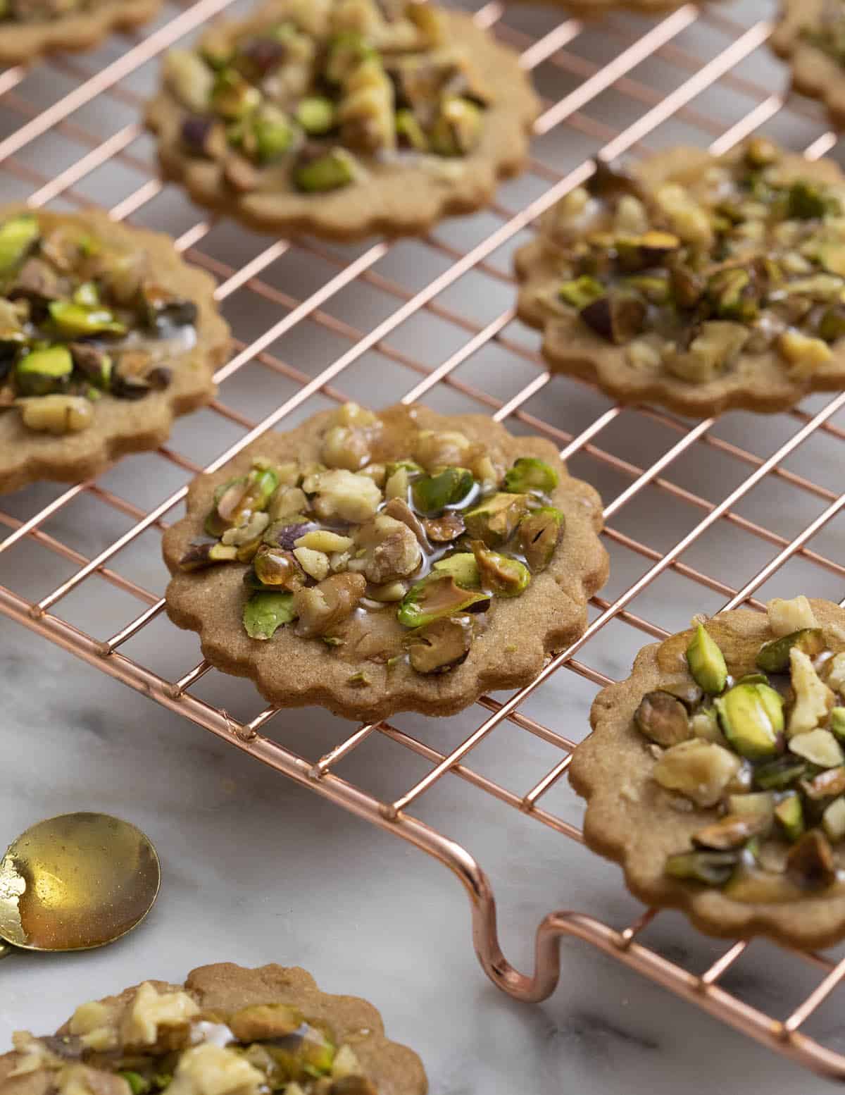 baklava cookies fresh out of the oven on a copper cooling rack.