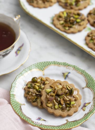 baklava cookies on a porcelain plate next to a tea cup.