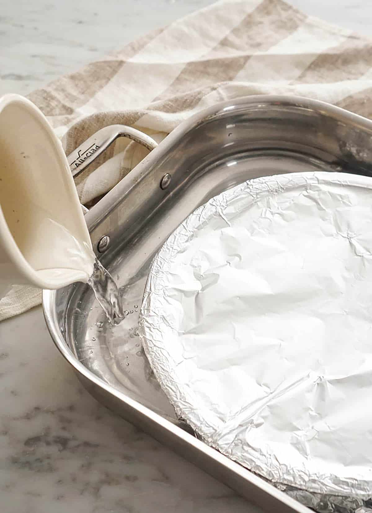 Water pouring into a roasting pan before it goes into the oven.