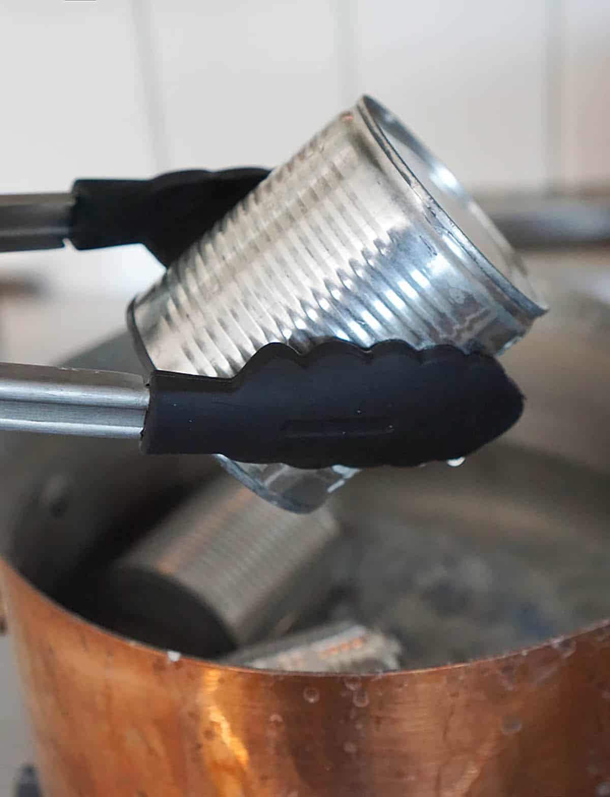 Sweetened condensed milk in a can going into a pot of water to make dulce de leche.