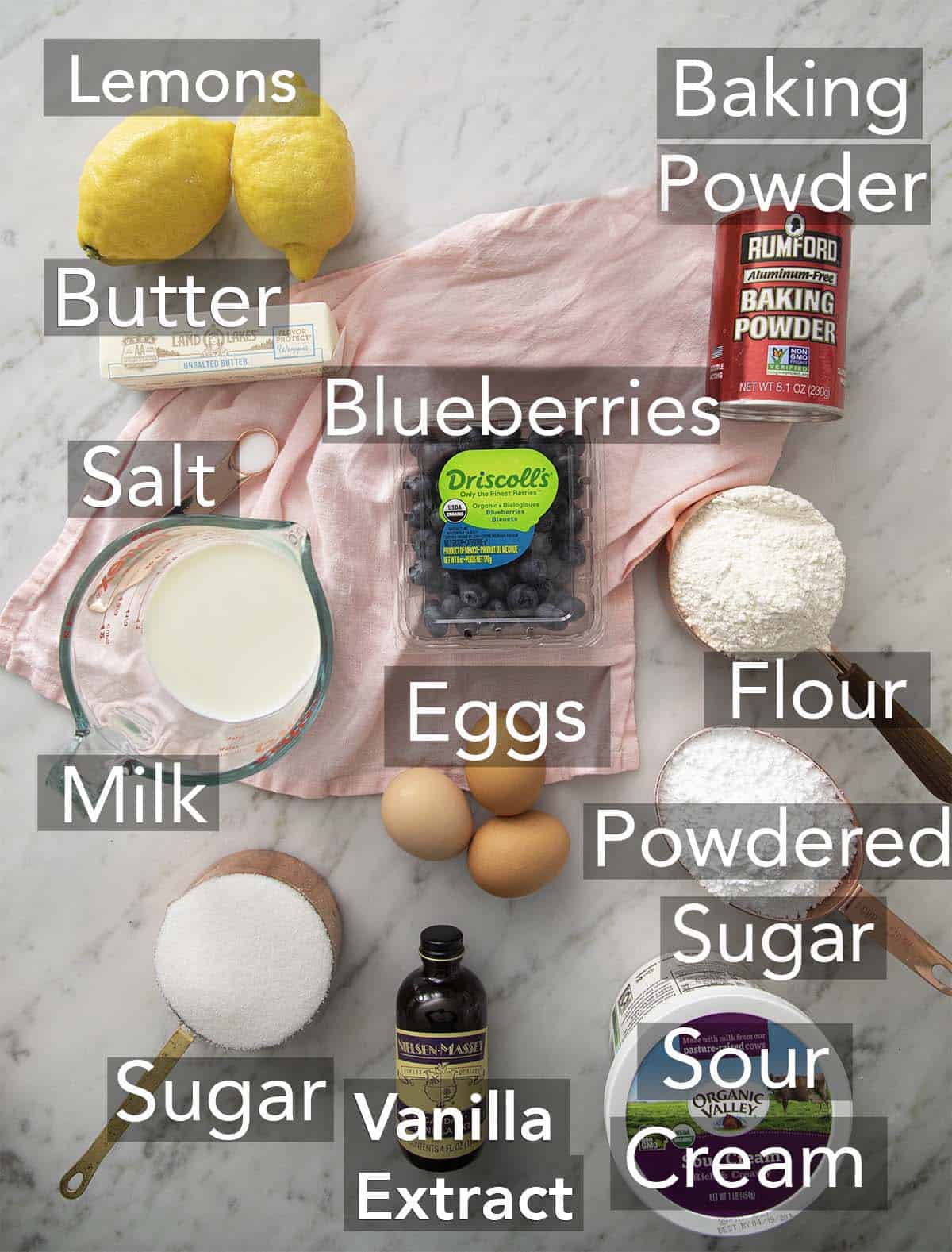 The ingredients for lemon blueberry cake on a marble surface.