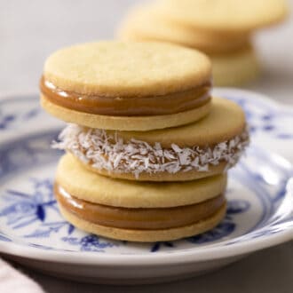 A stake of three alfajores on a blue and white plate.