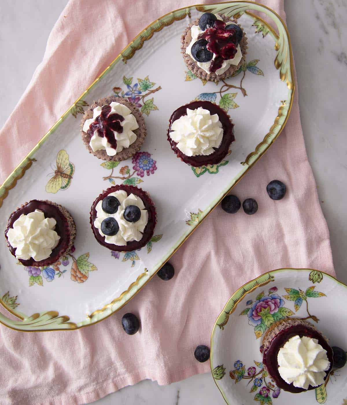 Porcelain dished with Blueberry mini cheesecakes decorated in different ways. 
