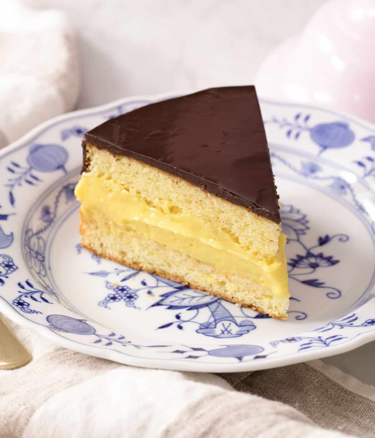 A piece of Boston cream pie on a blue and white plate.