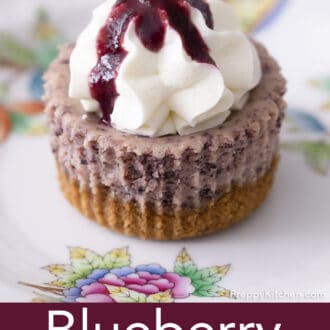 A mini blueberry cheesecake topped with whipped cream on a plate.