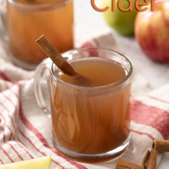 Pinterest graphic of two glass mugs of apple cider with cinnamon sticks.