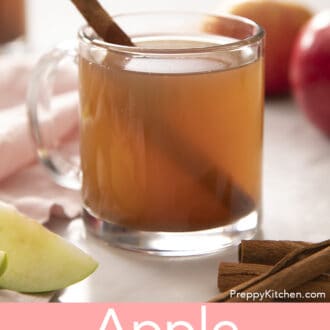 Pinterest graphic of a glass mug of apple cider next to cinnamon sticks.