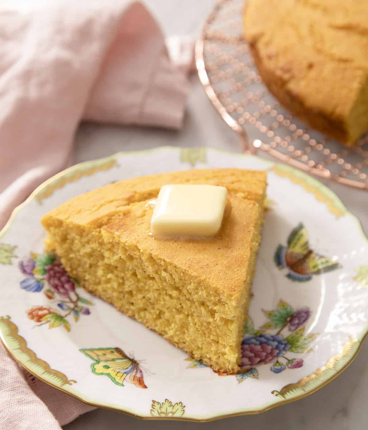 A slice of cornbread on a plate with butter on top.
