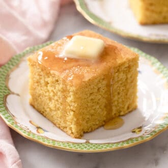 A square piece of cornbread topped with butter and honey.