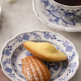 Pinterest graphic of two Madeleines on a blue and white plate next to a cup of tea.