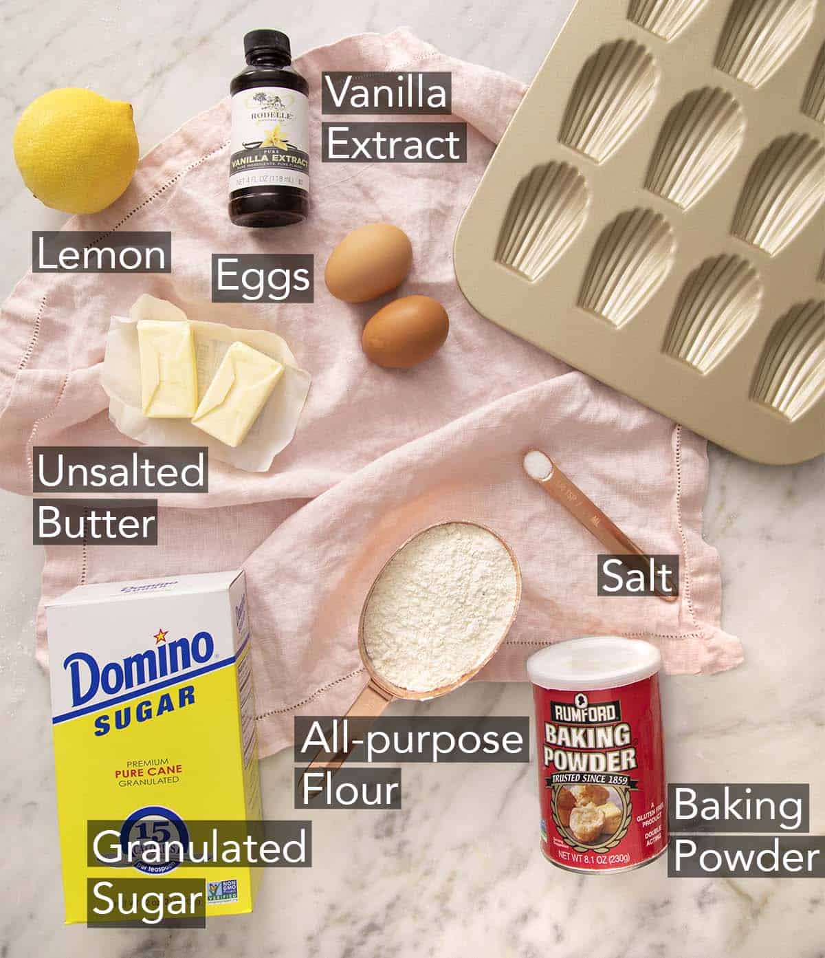 Ingredients to make Madeleines on a marble counter.
