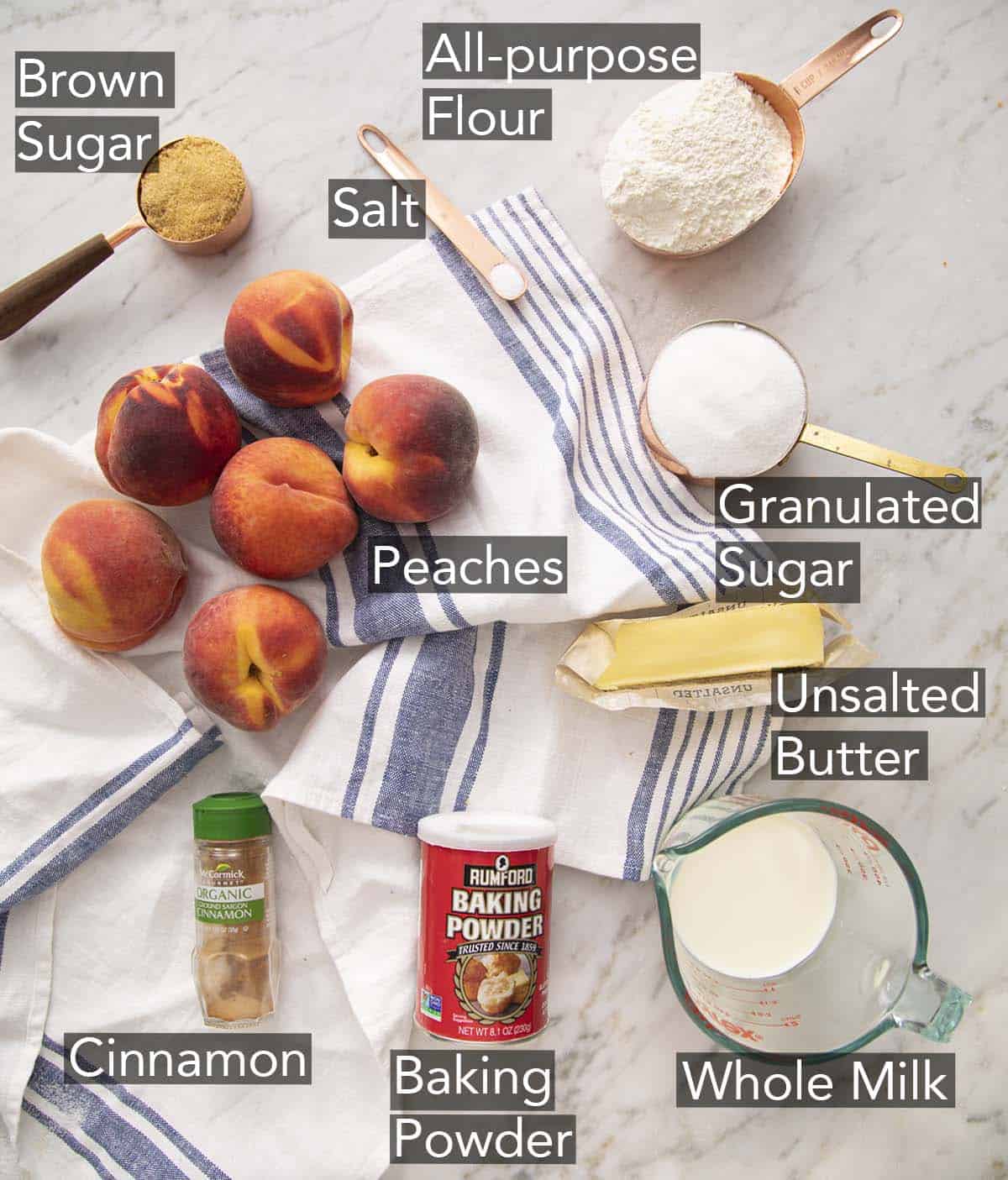 Ingredients to make peach cobbler on a marble counter.