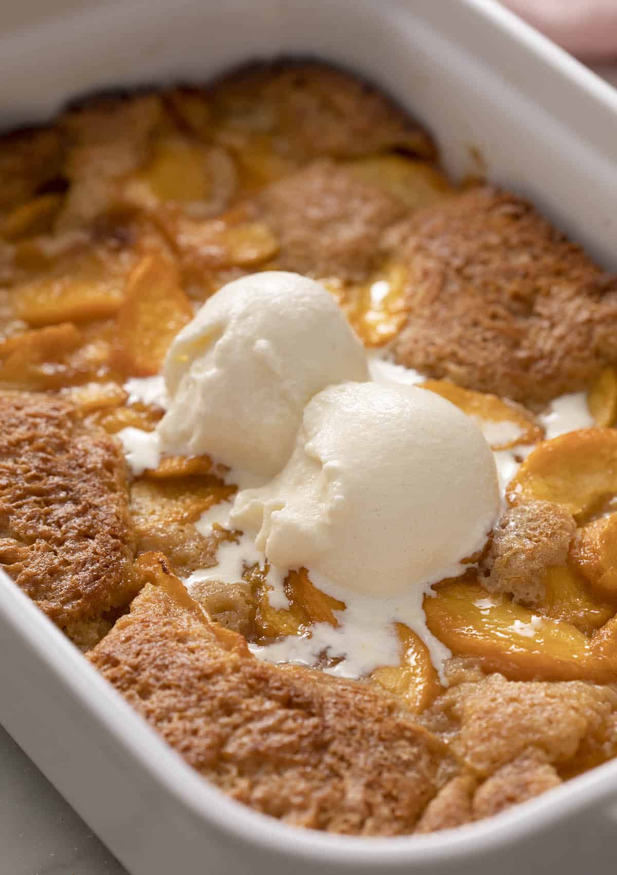 A delicious peach cobbler topped with two scoops of vanilla ice cream.