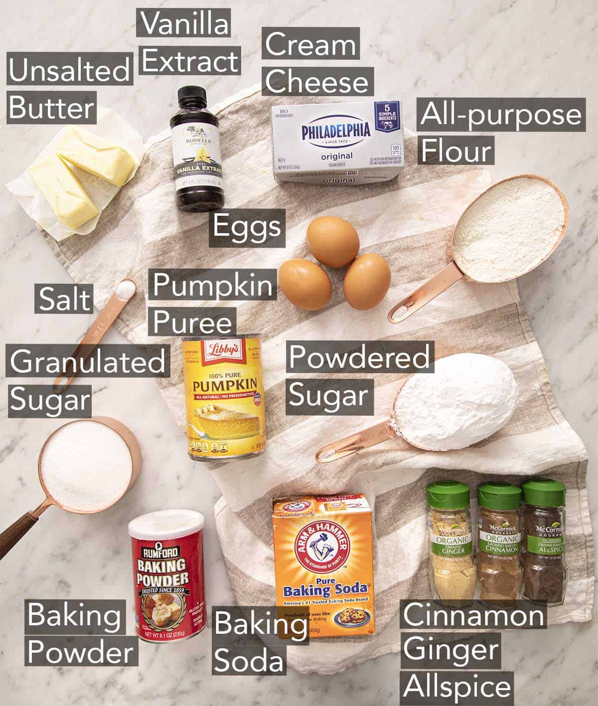 Ingredients to make a pumpkin roll cake on a marble counter.