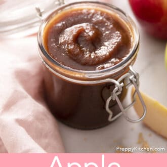 A container of apple butter next to a pink linen.