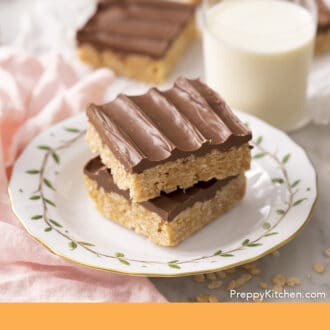 Pinterest graphic of two scotcheroos on a plate next to a glass of milk. More scotcheroos in the background.