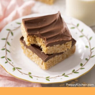 Pinterest graphic of two scotcheroos on a porcelain plate with a glass of milk.