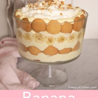 Pinterest graphic of a banana pudding in a glass trifle dish with a pink napkin beside it.