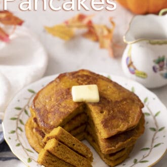 A stack of three pumpkin pancakes with a fork holding a piece resting on the plate.
