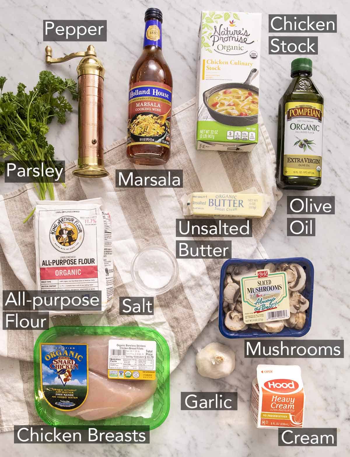 Ingredients to make chicken marsala on a marble counter.