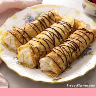 Pinterest graphic of rolled crepes on a plate with chocolate drizzle.