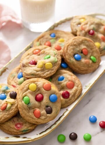 A group of M&M cookies on a porcelain serving tray.