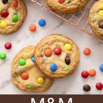 Pinterest graphic of several M&M Cookies on a copper cooling rack with three in front.
