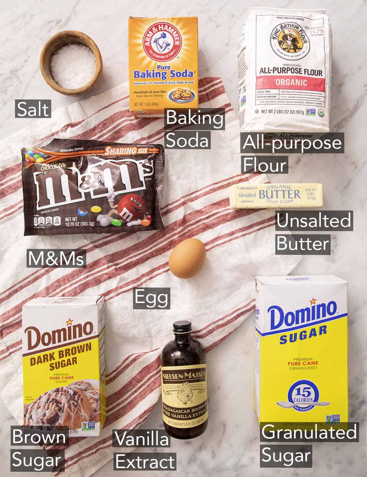Ingredients to make M&M cookies on a marble counter.