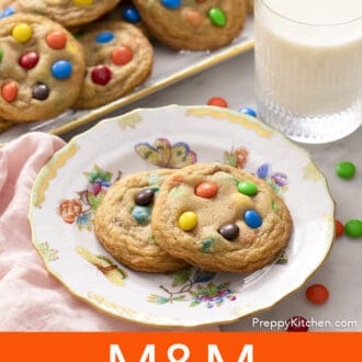 Pinterest graphic of two M&M Cookies on a floral plate with a glass of milk and platter of more cookies.