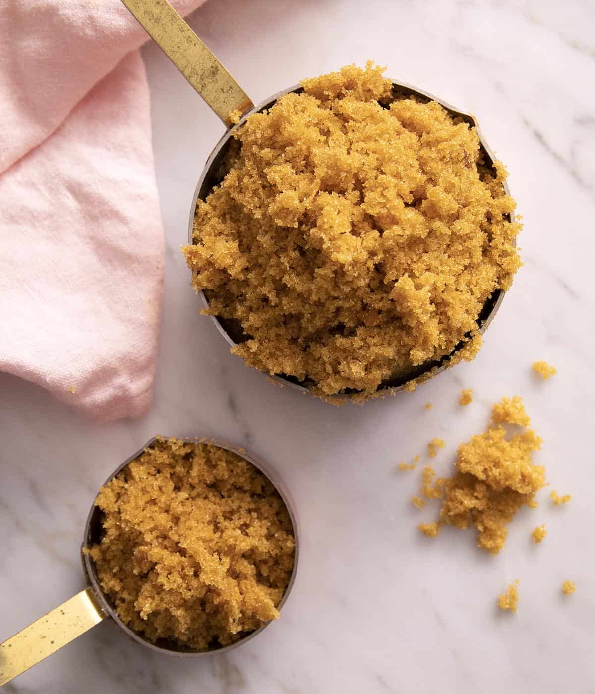 A top down view of two measuring cups with brown sugar.