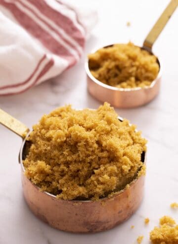 Two copper measuring cups full of homemade brown sugar.