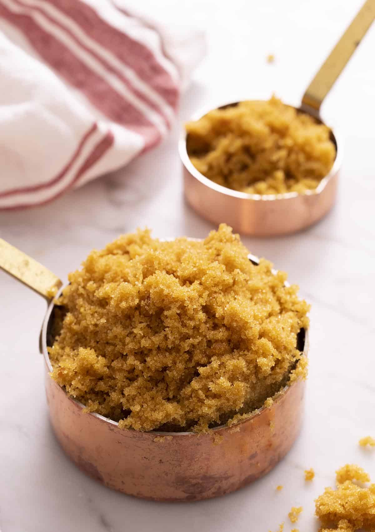 Two copper measuring cups full of homemade brown sugar.