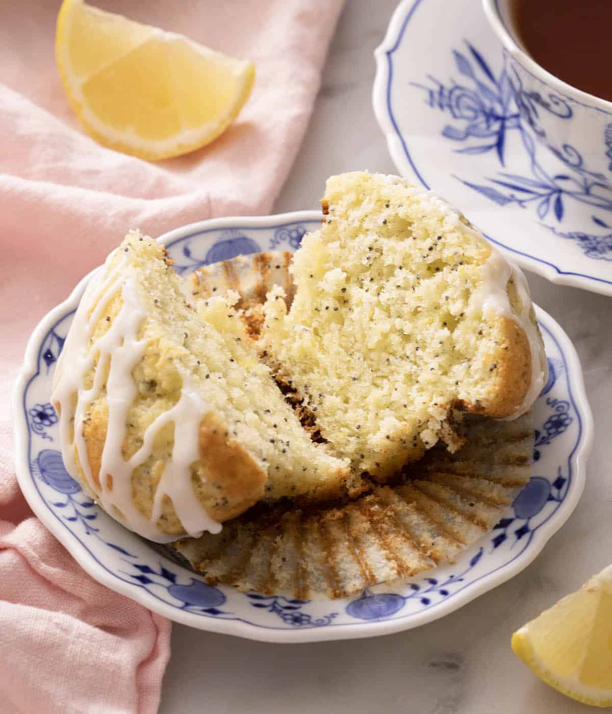 A lemon poppy seed muffin cut in half on a blue and white plate.