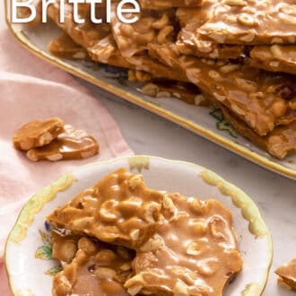 Pinterest graphic of pieces of peanut brittle stacked on a floral plate with a platter in the background.