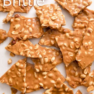Pinterest graphic of pieces of peanut brittle scattered on a white counter.