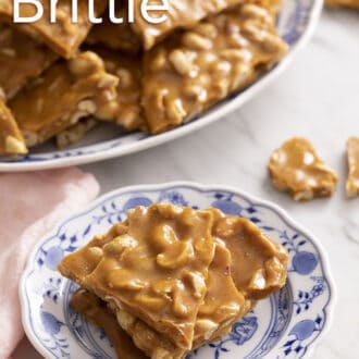 Pinterest graphic of pieces of peanut brittle stacked on a blue and white plate.